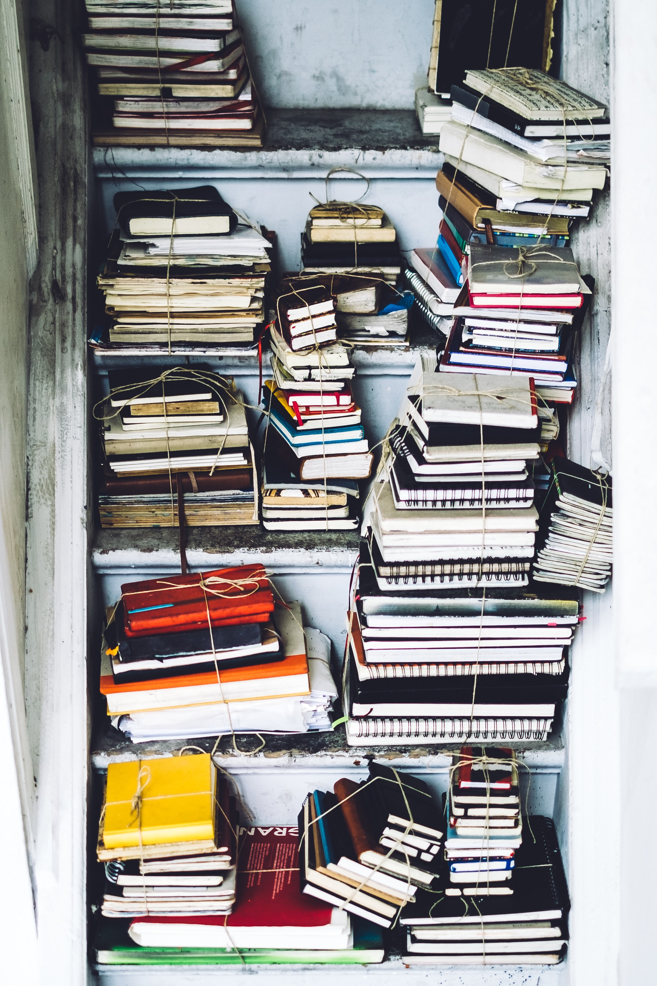 A cupboard filled with a large number of notebooks, tied together in piles with string.